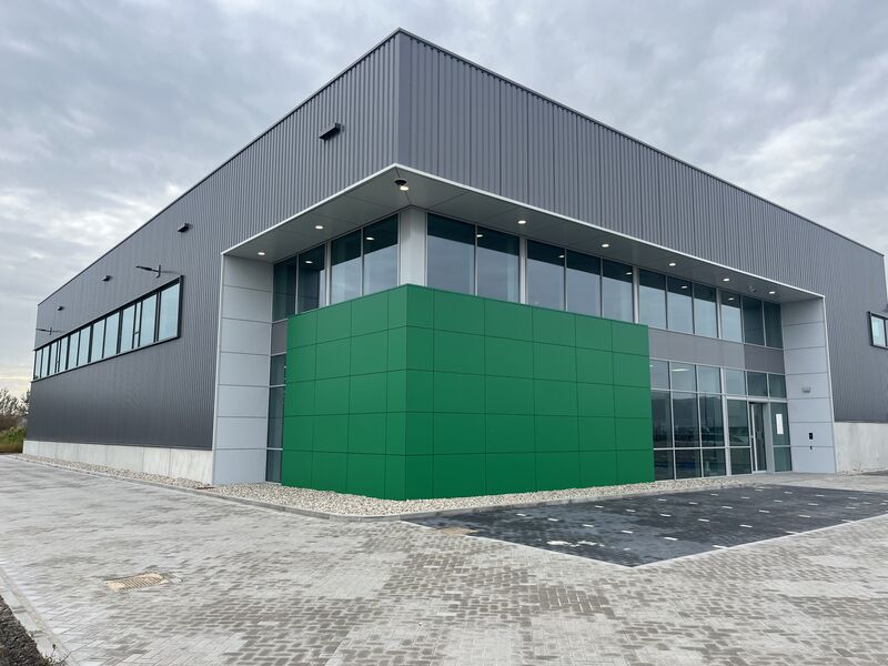 Bedrijfspand met grijze gevelbeplating en groen accentvlak, gerealiseerd door Saambouw