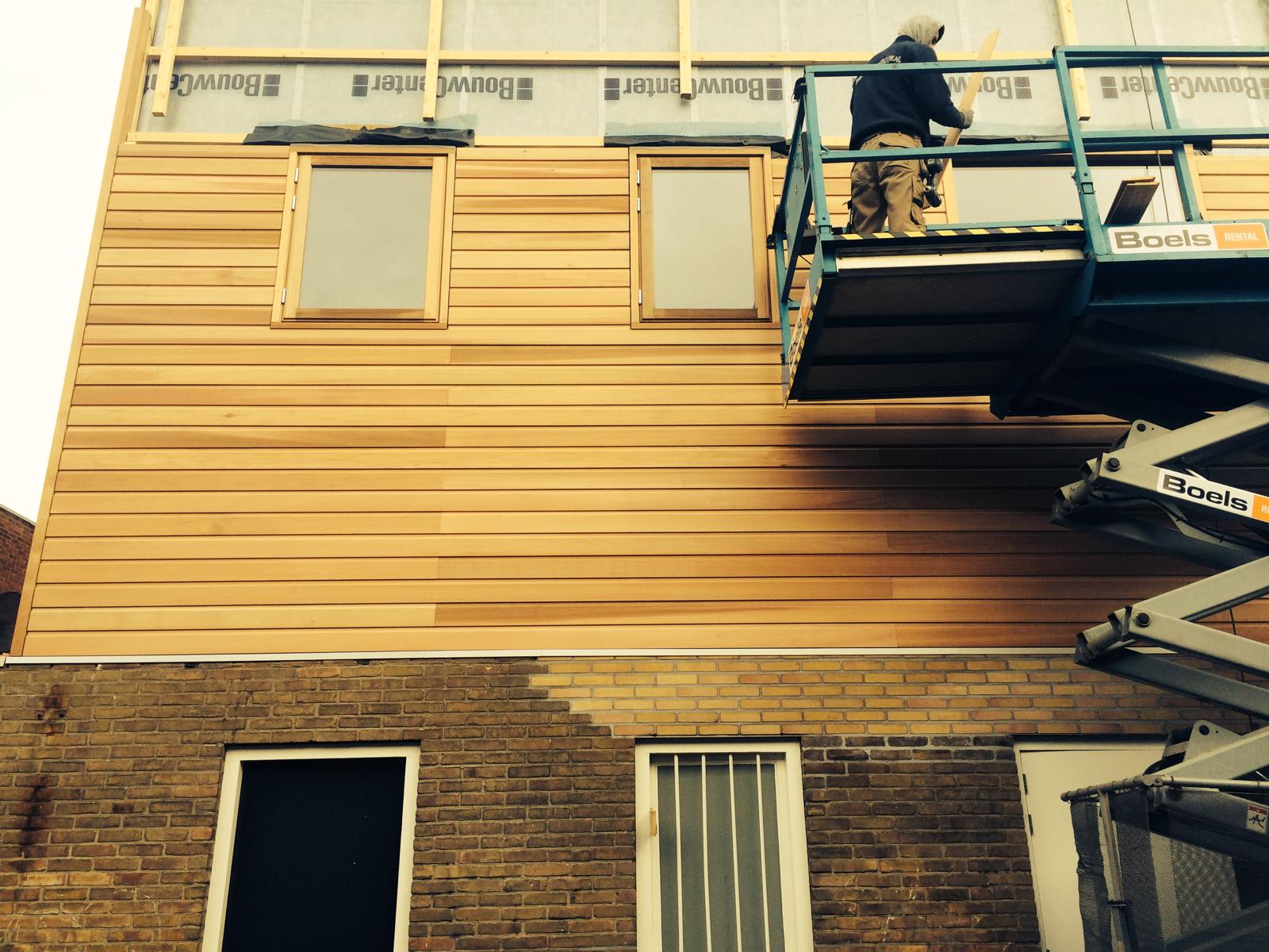 Vakman van Saambouw monteert houten gevelbekleding op een bouwproject